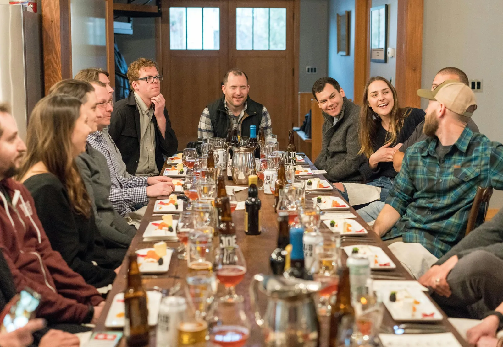 Picture of a group of friends or coworkers around a table eating and drinking and having fun